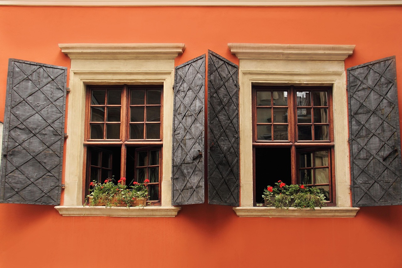 Maison avec volets ouverts et ciel ensoleillé.